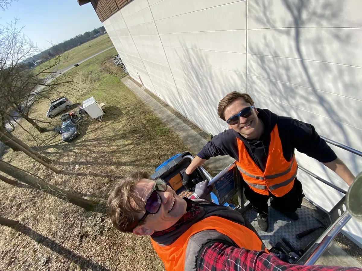 Die zwei Brüder in Warnwesten auf der Hebebühne bei Arbeiten an einem Gebäude